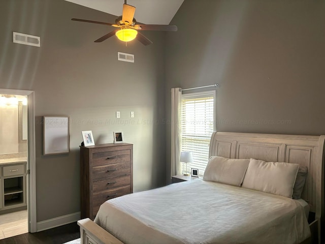 bedroom featuring hardwood / wood-style floors, ceiling fan, high vaulted ceiling, and ensuite bath