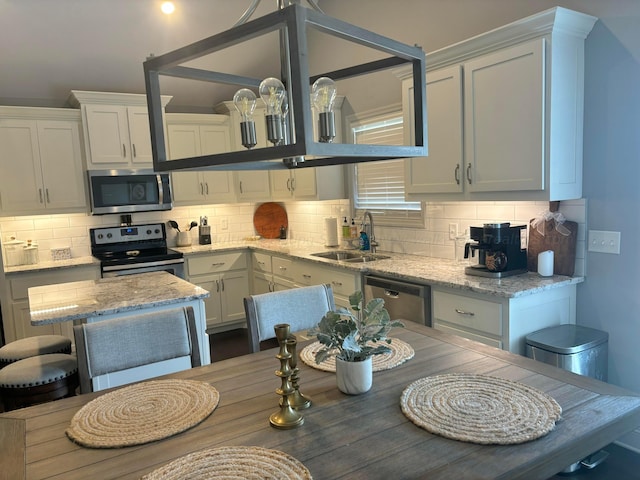 kitchen featuring tasteful backsplash, sink, white cabinets, and appliances with stainless steel finishes