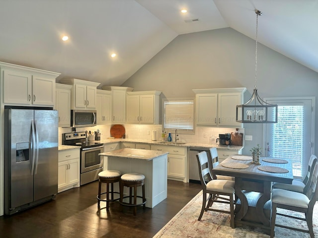 kitchen with dark wood-type flooring, high vaulted ceiling, decorative light fixtures, white cabinetry, and stainless steel appliances