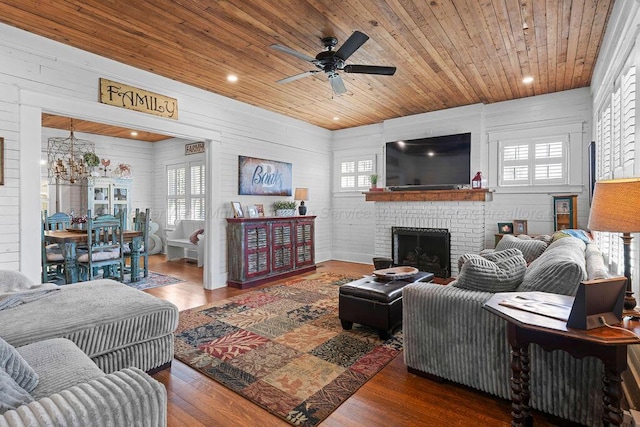 living room featuring wood finished floors, a healthy amount of sunlight, wooden ceiling, and ceiling fan with notable chandelier