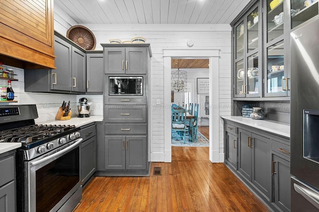 kitchen featuring dark wood-type flooring, light countertops, gray cabinets, appliances with stainless steel finishes, and an inviting chandelier