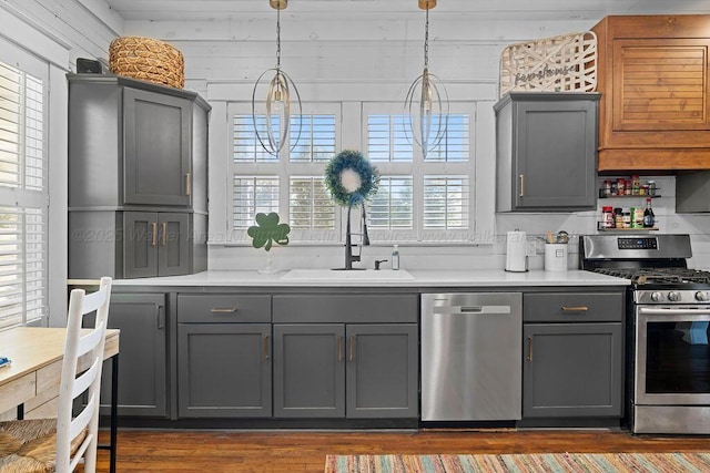 kitchen with gray cabinetry, stainless steel appliances, light countertops, and a sink