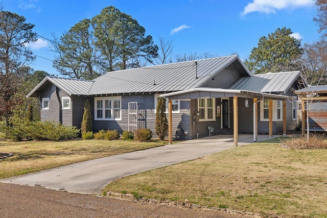 view of front of home featuring an attached carport, concrete driveway, a front yard, and metal roof