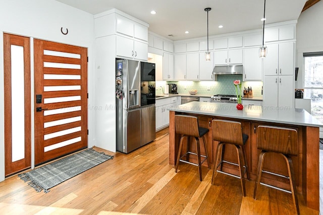 kitchen featuring stainless steel appliances, white cabinetry, and tasteful backsplash