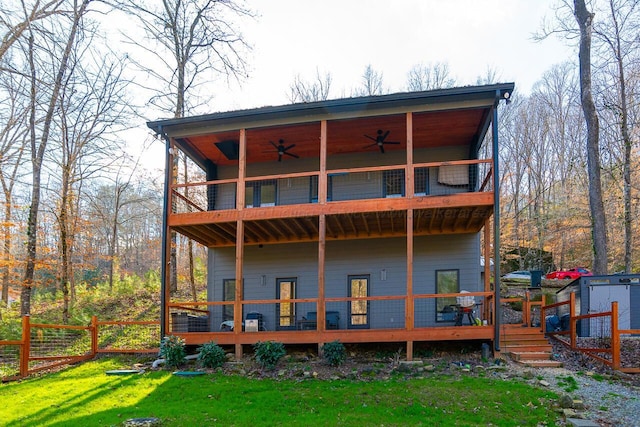 back of property with ceiling fan, a storage shed, a yard, and a wooden deck