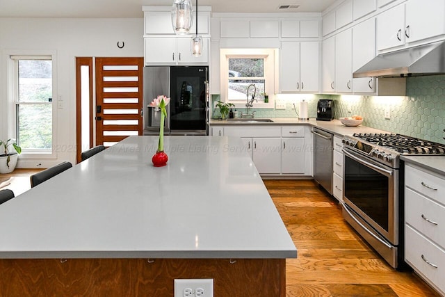 kitchen featuring decorative light fixtures, a center island, sink, and stainless steel appliances