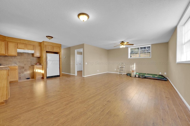 unfurnished living room featuring a textured ceiling, light hardwood / wood-style floors, and ceiling fan