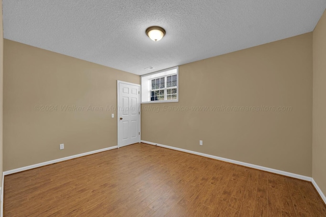 spare room featuring a textured ceiling and hardwood / wood-style flooring