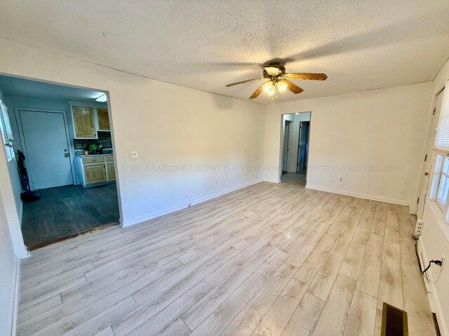 unfurnished room with visible vents, a textured ceiling, wood finished floors, baseboards, and ceiling fan