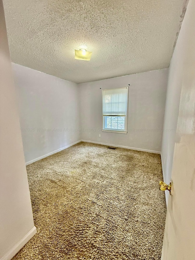 unfurnished room featuring visible vents, baseboards, carpet, and a textured ceiling