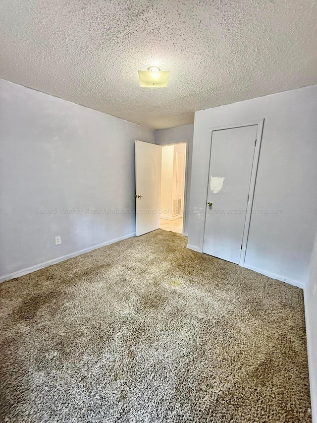 carpeted spare room with visible vents and a textured ceiling