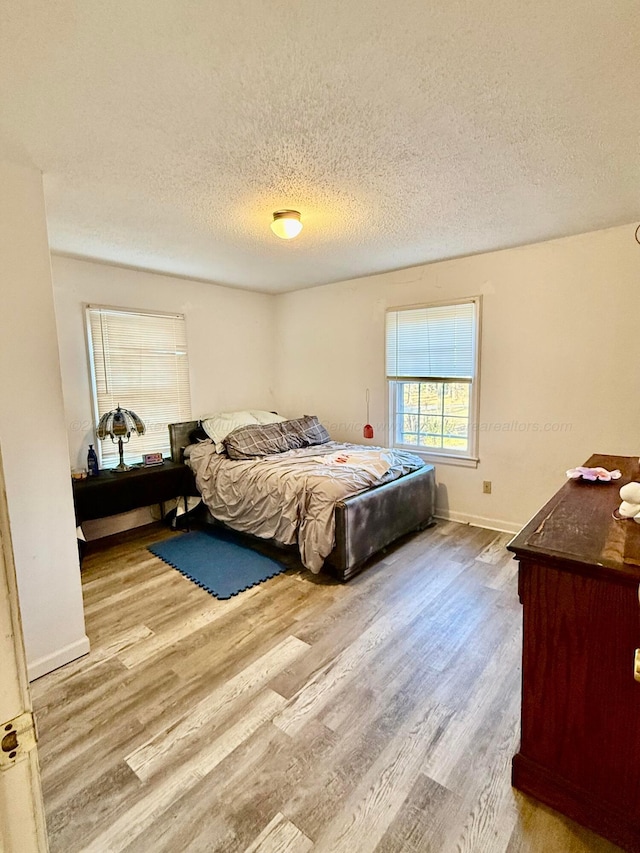 bedroom featuring wood finished floors, baseboards, and a textured ceiling