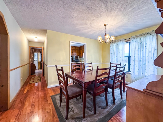 dining space with dark hardwood / wood-style flooring, a textured ceiling, and a chandelier