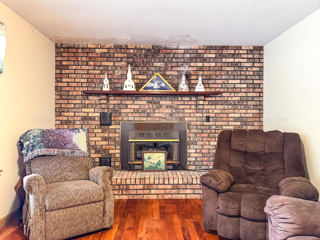 living room with wood-type flooring, a fireplace, and a textured ceiling