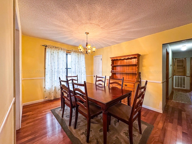 dining area featuring dark hardwood / wood-style flooring, a textured ceiling, and a chandelier