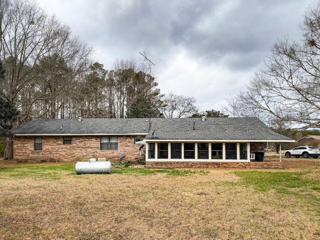 rear view of house featuring a sunroom and a lawn