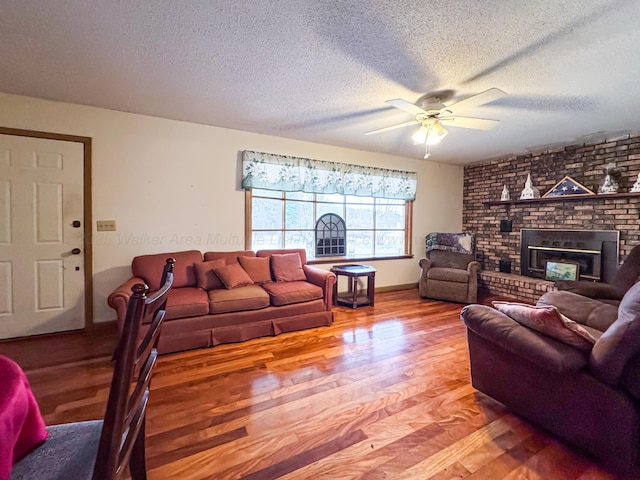 living room with ceiling fan, wood-type flooring, a fireplace, and a textured ceiling