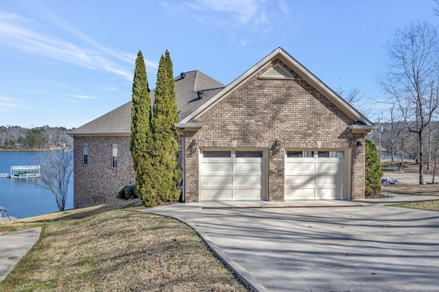 view of property exterior featuring a water view, brick siding, concrete driveway, and a shingled roof