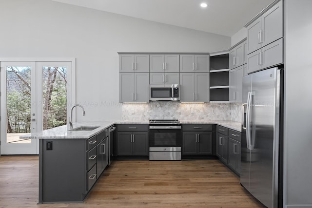 kitchen featuring kitchen peninsula, backsplash, stainless steel appliances, and gray cabinets