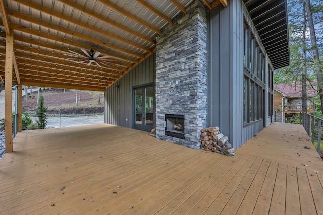 wooden deck featuring ceiling fan and an outdoor stone fireplace