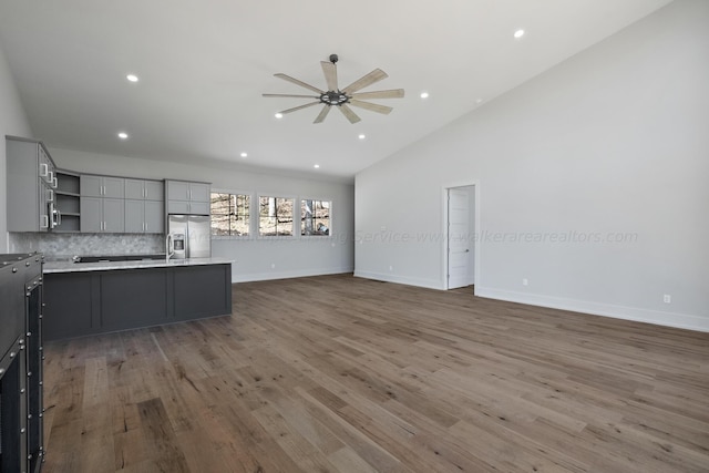 kitchen featuring decorative backsplash, ceiling fan, wood-type flooring, stainless steel fridge with ice dispenser, and lofted ceiling