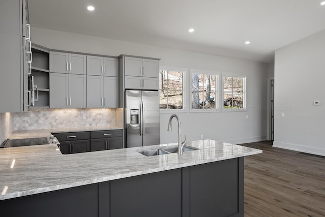 kitchen featuring stainless steel fridge, light stone counters, gray cabinetry, and sink