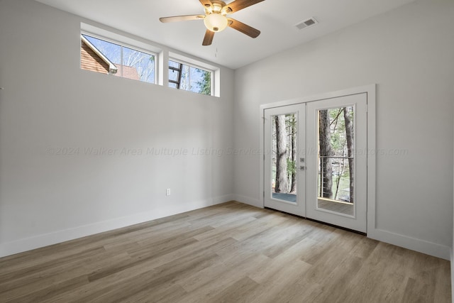 unfurnished room featuring french doors, light hardwood / wood-style flooring, a wealth of natural light, and ceiling fan