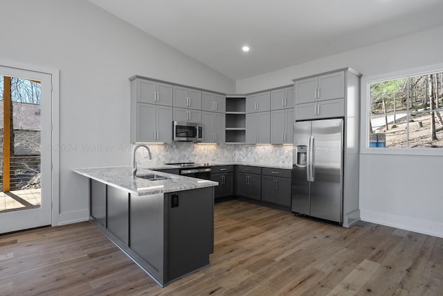 kitchen featuring lofted ceiling, sink, gray cabinets, appliances with stainless steel finishes, and kitchen peninsula