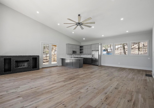 unfurnished living room featuring sink, light hardwood / wood-style floors, plenty of natural light, and ceiling fan