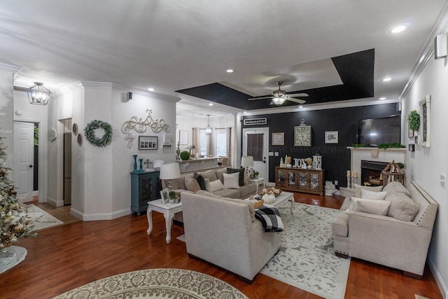 living room with ceiling fan, dark hardwood / wood-style flooring, crown molding, and a tray ceiling