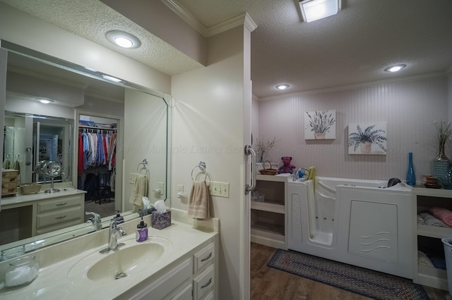 bathroom with hardwood / wood-style flooring, vanity, ornamental molding, and a textured ceiling