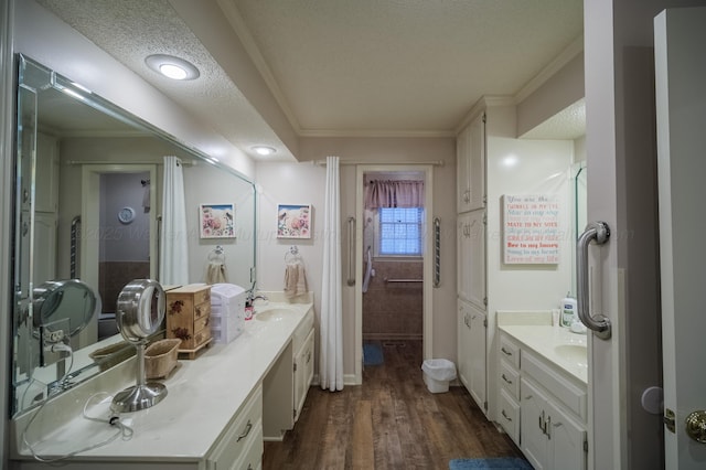 bathroom with vanity, wood-type flooring, ornamental molding, and a textured ceiling