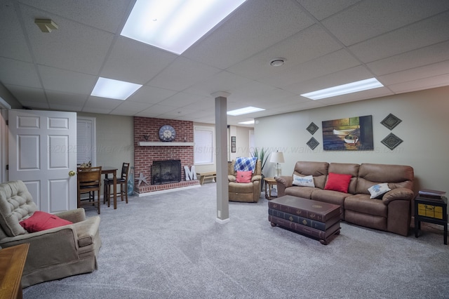 carpeted living room featuring a paneled ceiling and a brick fireplace