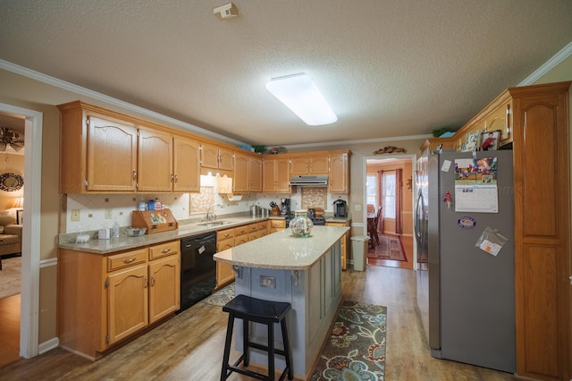 kitchen featuring sink, ornamental molding, black appliances, and a kitchen island