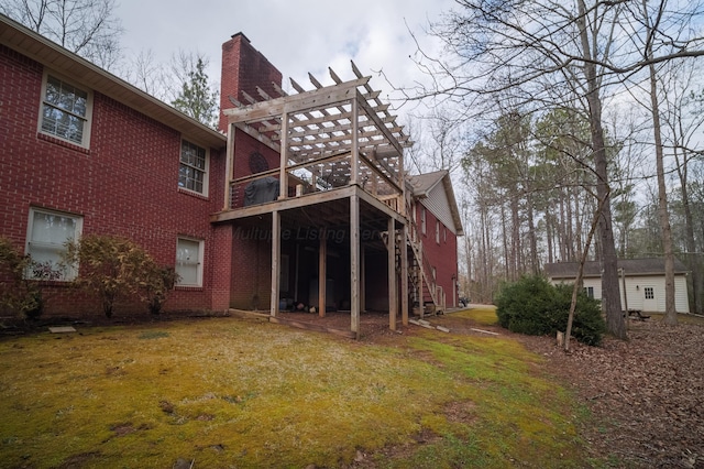 rear view of property with an outdoor structure, a yard, and a pergola