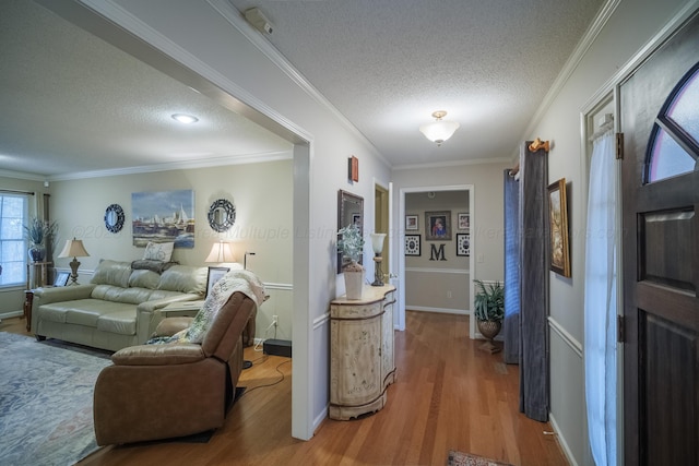 corridor featuring wood-type flooring, ornamental molding, and a textured ceiling