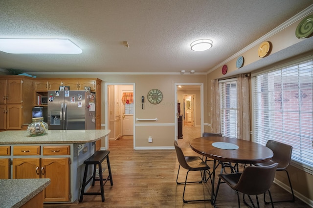 dining area with light hardwood / wood-style flooring, ornamental molding, and a textured ceiling