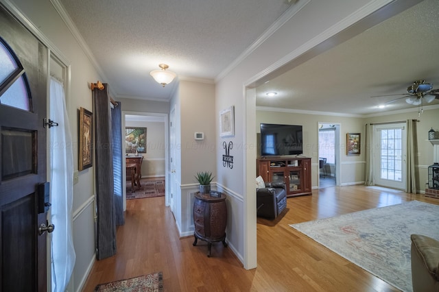 foyer with ceiling fan, light hardwood / wood-style flooring, ornamental molding, and a textured ceiling