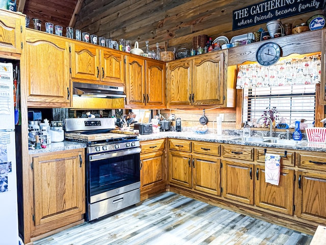 kitchen featuring lofted ceiling, sink, light hardwood / wood-style floors, white fridge, and gas stove