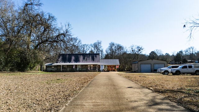 view of front of property featuring covered porch, a garage, and an outdoor structure