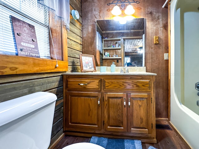 full bathroom featuring vanity, toilet, wooden walls, and bathing tub / shower combination