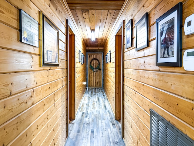 hallway with hardwood / wood-style flooring, wood walls, and wooden ceiling