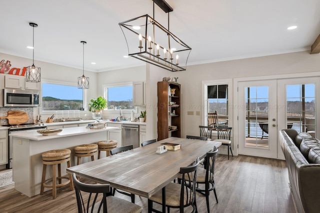 dining area featuring french doors, wood-type flooring, crown molding, and sink