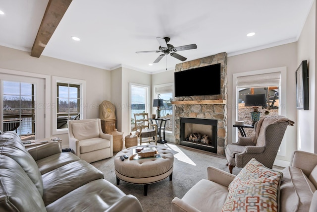 living room with crown molding, ceiling fan, a stone fireplace, and beamed ceiling