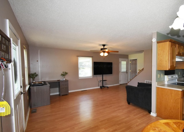 kitchen featuring extractor fan, a textured ceiling, light hardwood / wood-style flooring, and electric stove