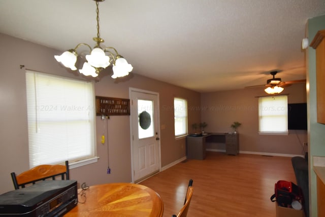 entryway with ceiling fan with notable chandelier, wood-type flooring, and a wealth of natural light