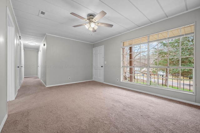 empty room featuring ceiling fan, crown molding, and light carpet