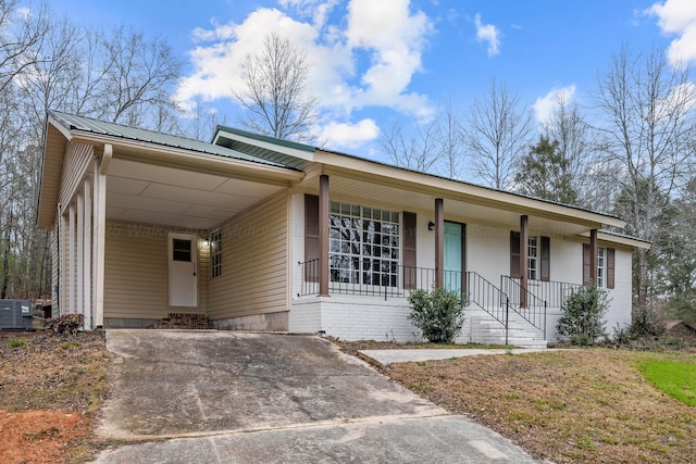 ranch-style home with cooling unit, covered porch, and a carport