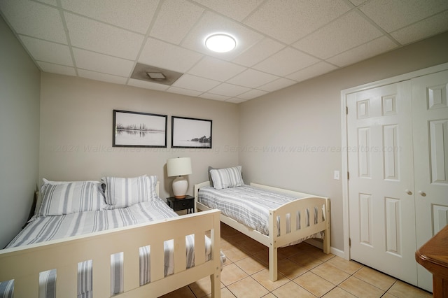 tiled bedroom with a closet and a drop ceiling