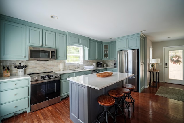 kitchen featuring decorative backsplash, stainless steel appliances, sink, dark hardwood / wood-style floors, and a kitchen island